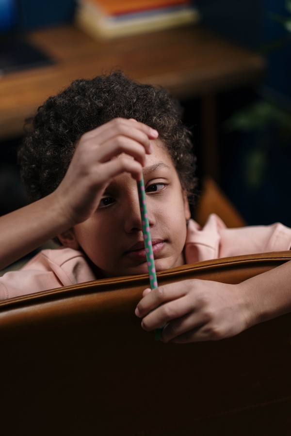 Ein Kind beobachtet einen Stift während einer Schulaufgabe
